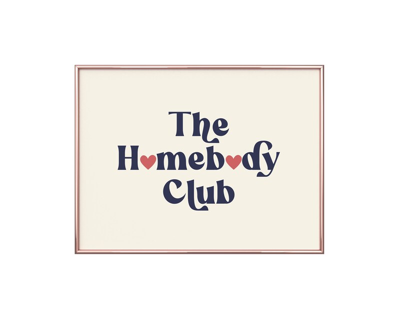 May include: A framed print with a cream background and navy blue text that reads "The Homebody Club" with two red hearts in the text.