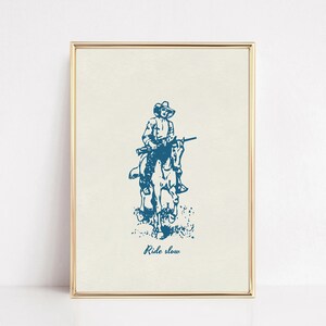 May include: A blue and white illustration of a cowboy riding a horse with a rifle. The text "Ride slow" is below the image.