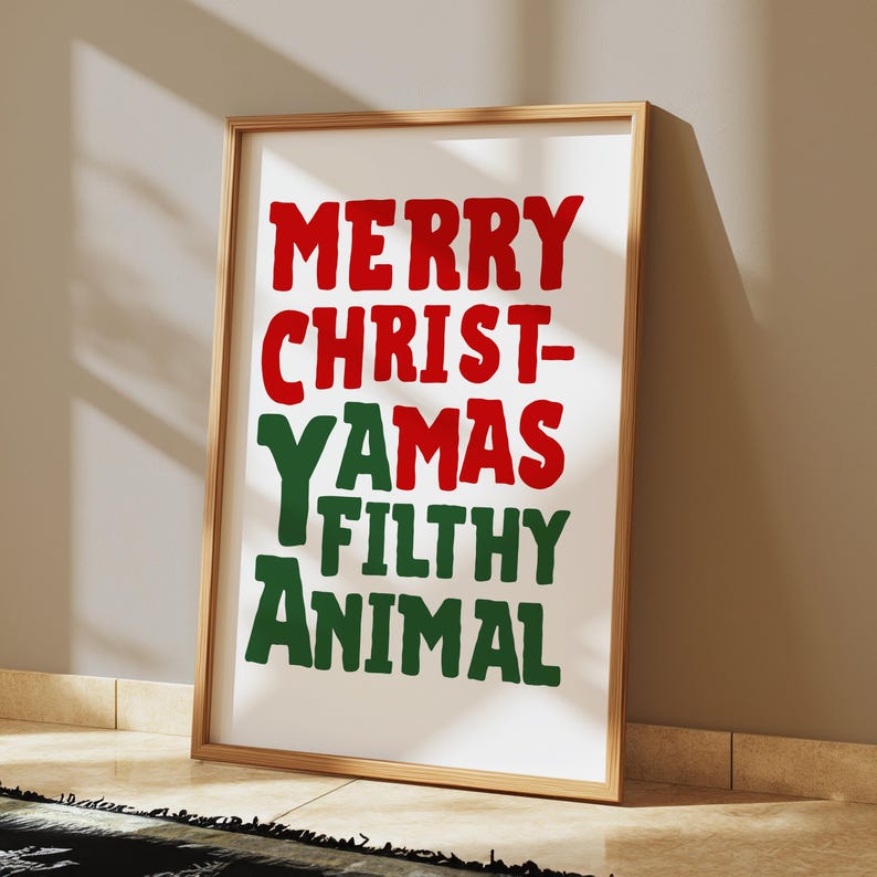 May include: A framed print with the text "Merry Christ-Yamas Filthy Animal" in red and green letters on a white background.