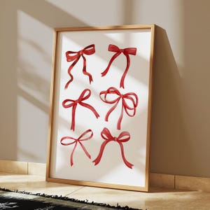 May include: A framed print with a white background and eight red watercolor bows.