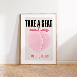 May include: A peach-shaped illustration with the text "TAKE A SEAT" above and "SWEET CHEEKS" below. The peach is pink and the text is black.