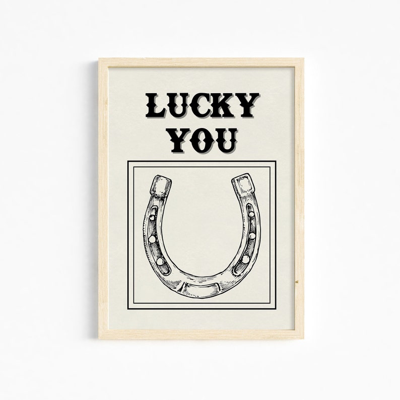 May include: A framed print with a black and white illustration of a horseshoe and the text "LUCKY YOU" in black.
