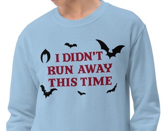 May include: A light blue sweatshirt with the text "I didn't run away this time" in maroon letters.  The text is surrounded by black bats.