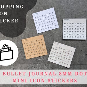 Op de afbeelding: Vier vellen mini-winkelicoonstickers in verschillende kleuren, waaronder wit, bruin en grijs. De stickers zijn gerangschikt op een grijze ondergrond. De tekst "SHOPPING ICON STICKER" en "BULLET JOURNAL 8MM DOT MINI ICON STICKERS" zijn ook zichtbaar.