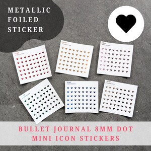 Op de afbeelding: Verschillende metallic folie stickers in hartvorm, in diverse kleuren, waaronder rood, goud en zwart, op een grijze ondergrond. Elke vel bevat 8 mm mini-hart-iconen. De tekst luidt "Metallic Foiled Sticker" en "Bullet Journal 8mm Dot Mini Icon Stickers."