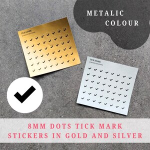 Op de afbeelding: Twee metallic sticker vellen, één goudkleurig en één zilverkleurig, elk bedekt met kleine zwarte vinkjes. Het gouden vel heeft een logo met de tekst "TICK MARK KUMASHE CREATIONS". De tekst "8MM DOTS TICK MARK STICKERS IN GOLD AND SILVER" staat onderaan.