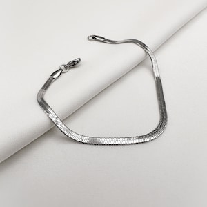May include: A silver snake chain bracelet with a clasp closure.