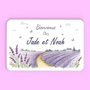 Peut inclure: Un panneau rectangulaire avec une illustration à l'aquarelle d'un champ de lavande, d'un chemin et d'une petite maison. Le panneau porte l'inscription "Bienvenue Chez Jade et Noah" en écriture cursive, avec des papillons et des nuages.