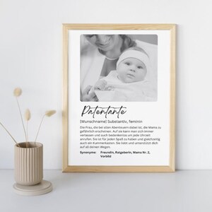 May include: A black and white photograph of an adult woman holding a baby. The photo is framed in a light wood frame. The text below the photo reads "Patentante [Wunschname] Substantiv, feminin Die Frau, die bei allen Abenteuern dabei ist, die Mama zu gefährlich erscheinen. Auf sie kann man sich immer verlassen und auch bedenkenlos um jede Uhrzeit anrufen. Sie ist für jeden Spaß zu haben und gleichzeitig auch ein Kummerkasten. Sie liebt und unterstützt dich auf all deinen Wegen. Synonyme: Freundin, Ratgeberin, Mama Nr. 2, Vorbild"