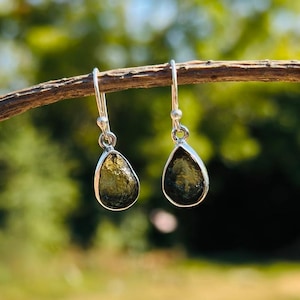 May include: A pair of silver dangle earrings with teardrop-shaped green gemstones.