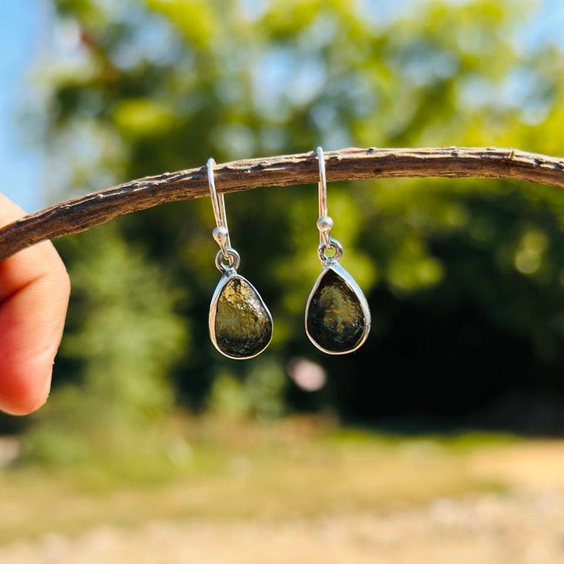 May include: A pair of silver dangle earrings with teardrop-shaped green gemstones.