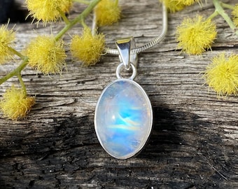 May include: A silver chain necklace with a pendant featuring a large oval-shaped moonstone. The moonstone is iridescent with a blue and white color.