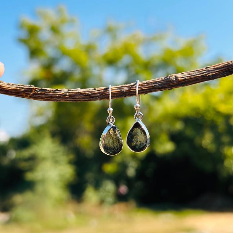 May include: A pair of silver dangle earrings with teardrop-shaped green gemstones.