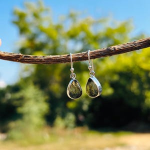 May include: A pair of silver dangle earrings with teardrop-shaped green stones.