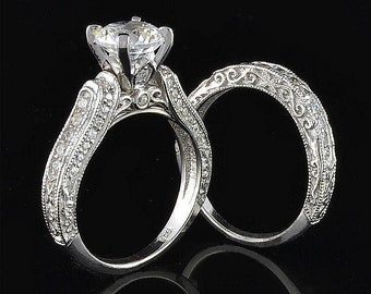 May include: A pair of silver engagement rings with a large, round, clear center stone. The rings are set with smaller, clear stones around the band.