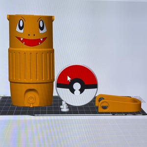 May include: An orange water cooler with a Charmander face design, a red and white Pok&eacute;ball, and a matching orange handle. The cooler has a spigot and vertical ridges. The design is 3D printed.
