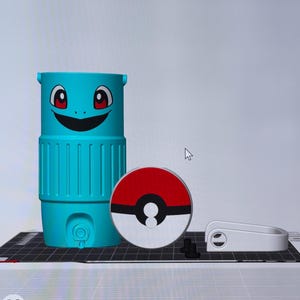 May include: A teal, cylindrical container with a cartoon face and a red and white Pokeball. The container has a smiling face with red eyes. A white handle and small black pieces are also present.