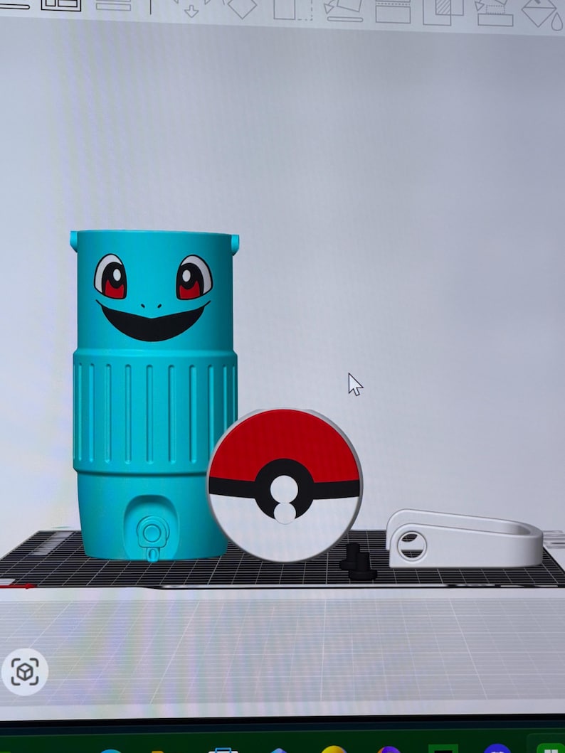 May include: A teal, cylindrical container with a cartoon face and a red and white Pokeball. The container has a smiling face with red eyes. A white handle and small black pieces are also present.