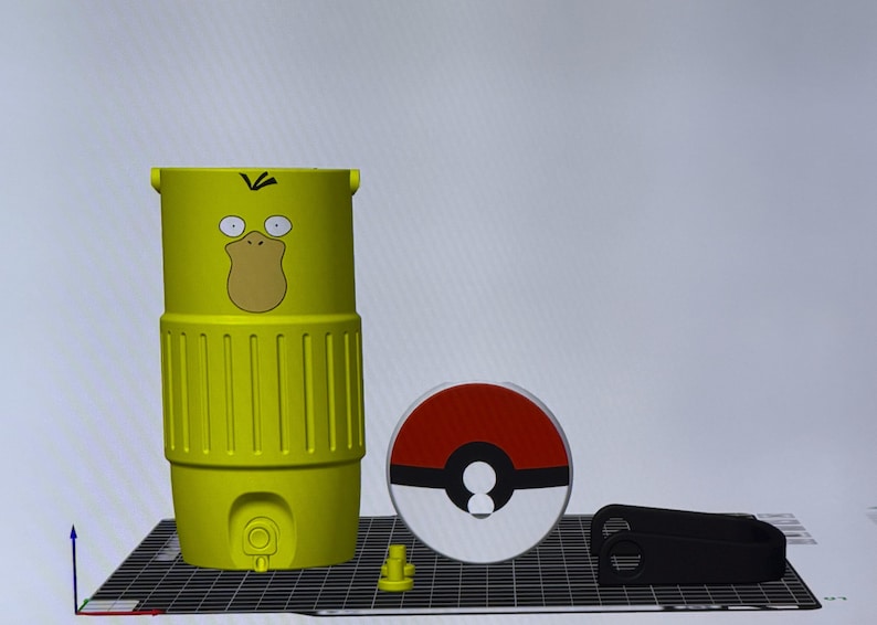 May include: A yellow Psyduck-themed water bottle with a cartoon face, a red and white Pok&eacute; Ball, and a black accessory. The bottle has a cylindrical shape with vertical grooves and a handle. The Pok&eacute; Ball is a circular design.
