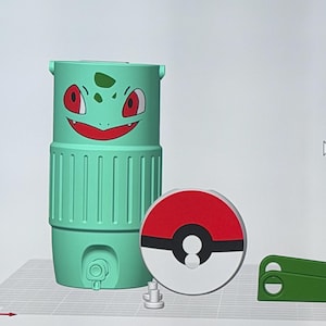 May include: A collection of 3D-printed items featuring a Bulbasaur-themed water bottle, a Pok&eacute; Ball-shaped lid, and a green clip. The Bulbasaur bottle is light green with a smiling face. The Pok&eacute; Ball lid is red and white.