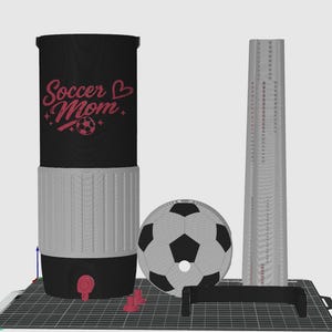 May include: A black and gray insulated water bottle with the text "Soccer Mom" in pink script. A soccer ball, a tall, thin, gray object, and a black handle are also present. The bottle has a red tap and a gray base.