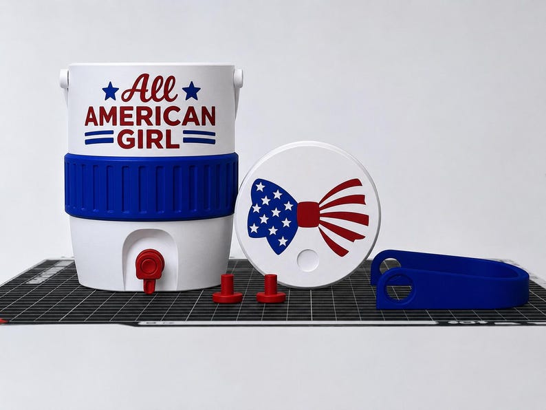 May include: A white and blue cooler with the text "All AMERICAN GIRL" in red and blue. The cooler has a blue band and a red spigot. A white lid with a bow tie design in red and blue, two red stoppers, and a blue handle are also present.