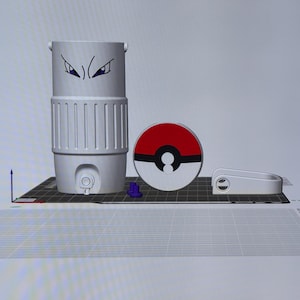 May include: A 3D-printed, light gray water bottle with a cartoon eye design, a red and white circular object, and a white handle. The water bottle has vertical ridges and a small spout. The circular object resembles a Pokeball.