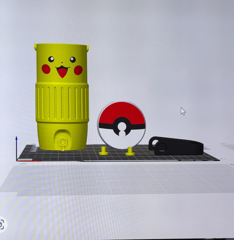 May include: A yellow Pikachu-themed tumbler with a smiling face and red cheeks, a red and white Pokeball, and a black object. The tumbler has a ribbed design and a small circular opening at the bottom. The Pokeball is round with a black center.