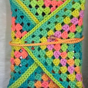 May include: A crocheted pouch with a granny square pattern in shades of green, pink, orange, and yellow. The pouch is folded over and secured with a button.