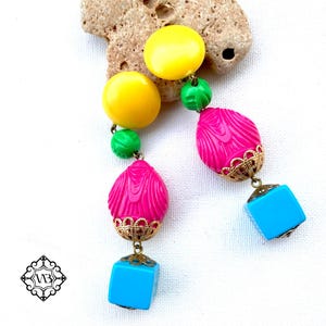 May include: A pair of colorful dangle earrings with yellow, green, pink, and blue beads. The earrings have a gold-tone metal design.