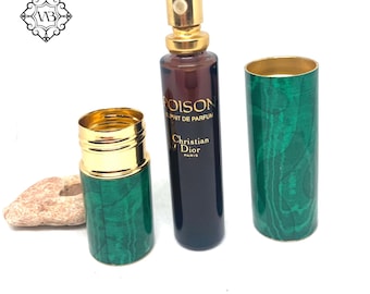 Könnte beinhalten: Ein Parfümflakon mit goldfarbenem Deckel und der Aufschrift "POISON Esprit de Parfum Christian Dior Paris" auf der dunkelbraunen Flasche. Die Flasche befindet sich in einem grünen Gehäuse mit Malachitmuster und goldenen Akzenten. Zwei weitere Malachit-Gehäuse sind ebenfalls vorhanden.
