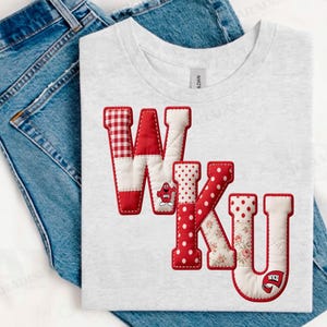 May include: A light gray t-shirt featuring the letters "WKU" in red and white patchwork fabric. The "W" has a red and white gingham pattern, the "K" has red polka dots, and the "U" has a floral pattern. A small logo is on the "K" and "U".