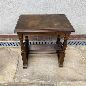 May include: A dark brown wooden side table with a shelf. The table has turned legs and a simple design.