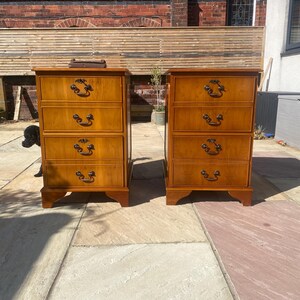 May include: Two wooden four-drawer chests with brass hardware. The chests are a rich brown colour and have a traditional style.