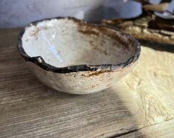 May include: A small, white ceramic bowl with a brown rim and a speckled glaze. The bowl is 4 inches in diameter.