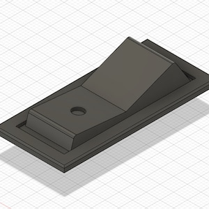 Puede incluir: Un interruptor de palanca de plástico negro con una base rectangular y un balancín elevado y angulado. El interruptor tiene un pequeño agujero en el centro del balancín.