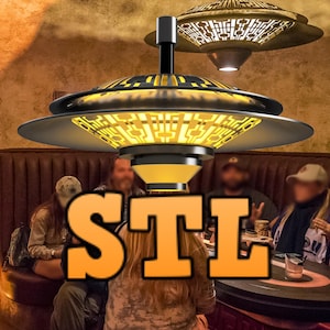Peut inclure: Un groupe de personnes assises autour d'une table avec un luminaire unique et futuriste suspendu au-dessus d'eux. Le luminaire a une forme circulaire et étagée avec un schéma de couleurs noir et or. Le texte "STL" est superposé à l'image dans une grande police orange.