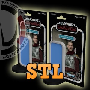 Puede incluir: Dos exhibidores de figuras de acción de Star Wars Mandalorian con Marshal Cobb Vanth. Las figuras están en embalajes de estilo retro con el texto "STAR WARS MANDALORIAN" y "Kenner". Los exhibidores tienen un diseño azul y blanco y están sobre bases negras.