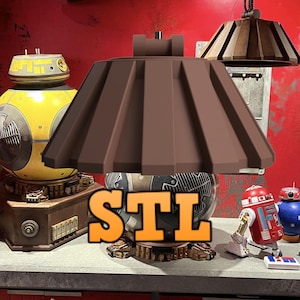 May include: A brown lampshade with a unique design, featuring a series of vertical ridges. The lampshade is sitting on a round base with a gold finish. The word "STL" is printed in orange letters on the base. The lampshade is surrounded by other objects, including a yellow robot and a red and white robot.