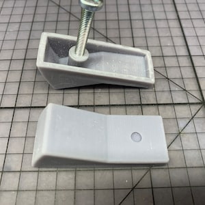 May include: Two gray plastic furniture feet with a screw hole in the top of one foot.