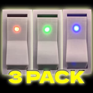 Puede incluir: Tres interruptores basculantes blancos con luces LED. Los interruptores tienen luces rojas, verdes y azules. El texto "3 PACK" está impreso en amarillo debajo de los interruptores.