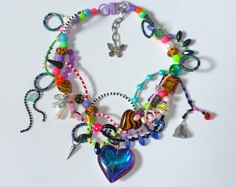 May include: A multi-layered necklace with a variety of colorful beads, charms, and a large iridescent heart pendant. The necklace features a butterfly charm, tiger print beads, and a variety of other decorative elements.