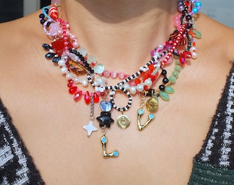 May include: A layered necklace with multiple strands of beads in various colors, including red, pink, white, black, and green. The necklace features charms in the shape of a heart, star, and the letters "LOVE".