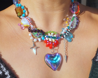 May include: A colorful layered necklace with a variety of beads, charms, and a large iridescent heart pendant.