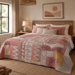 Könnte beinhalten: Eine Tagesdecke mit geometrischem Patchwork-Muster in den Farben Altrosa, gedämpftem Gelb, Weiß und Grau. Die Decke zeigt eine Vielzahl von Formen wie Dreiecke, Zickzacklinien und einfarbige Blöcke mit einer gesteppten Textur auf der Oberfläche.
