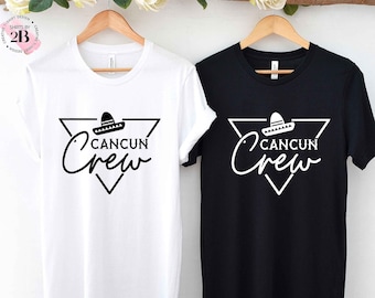 May include: Two t-shirts, one white and one black, with a graphic design of a sombrero inside a triangle with the text "Cancun Crew" in a script font.