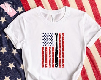 May include: White t-shirt with a distressed American flag design featuring a baseball bat in the center.