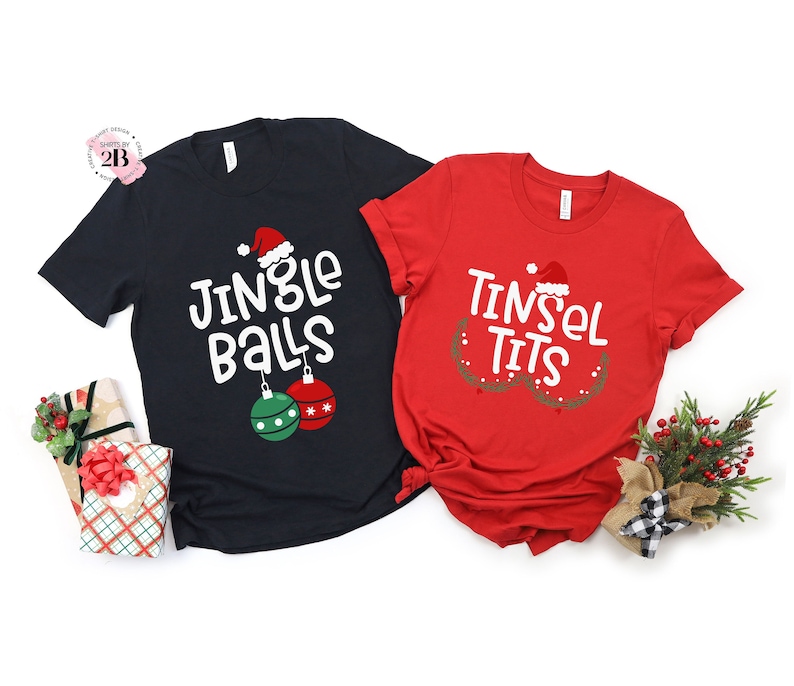 May include: Two black and red t-shirts with a Christmas theme. The black shirt says "Jingle Balls" with a Santa hat and baubles. The red shirt says "Tinsel Tits" with a Santa hat and tinsel.