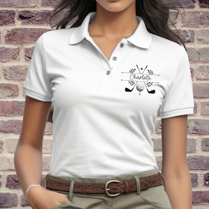 May include: White polo shirt with a black golf-themed design featuring crossed golf clubs, a golf ball, and the name "Charlotte".