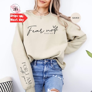 Peut inclure: Sweat-shirt couleur sable avec l'inscription "Fear not" et "Isaïe 41:10" en écriture noire. La manche porte l'inscription "For I am with you". Le sweat-shirt est de style décontracté.